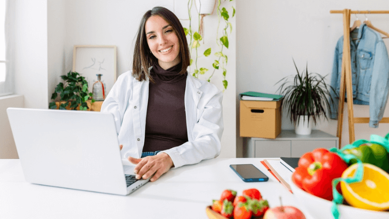 Smiling dietitian woman looking at camera sitting at hospital workplace. Nutrition, diet and professional healthcare worker concept